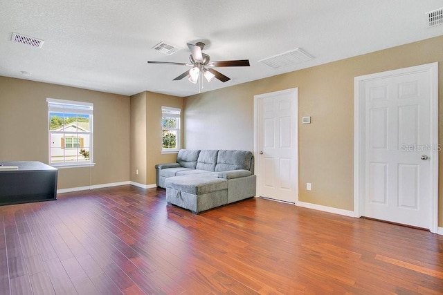 living room featuring hardwood / wood-style flooring, ceiling fan, and a textured ceiling