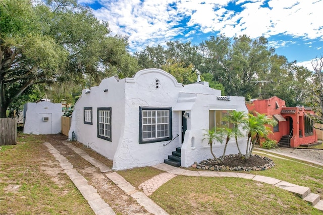 adobe home featuring a shed and a front lawn