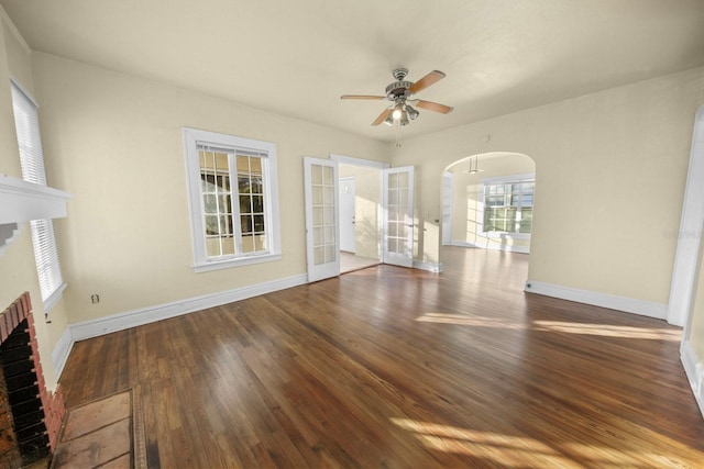 unfurnished living room with ceiling fan, a fireplace, and dark wood-type flooring