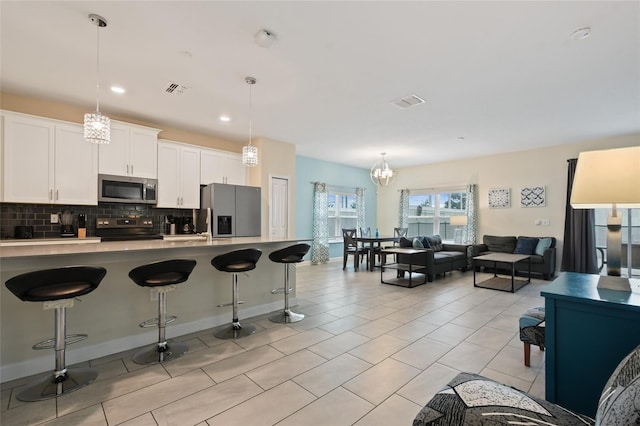 kitchen featuring white cabinets, decorative light fixtures, stainless steel appliances, and a breakfast bar