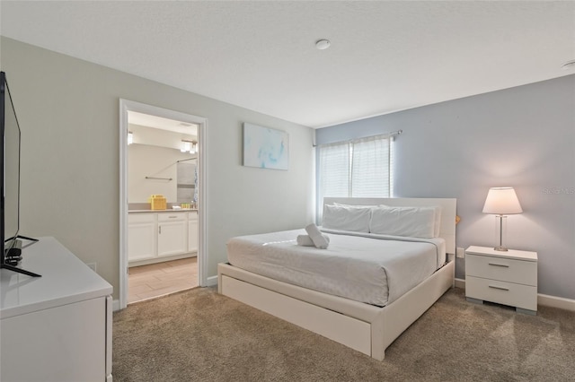 bedroom with ensuite bathroom and dark carpet