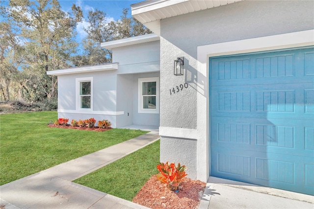 entrance to property featuring a garage and a lawn