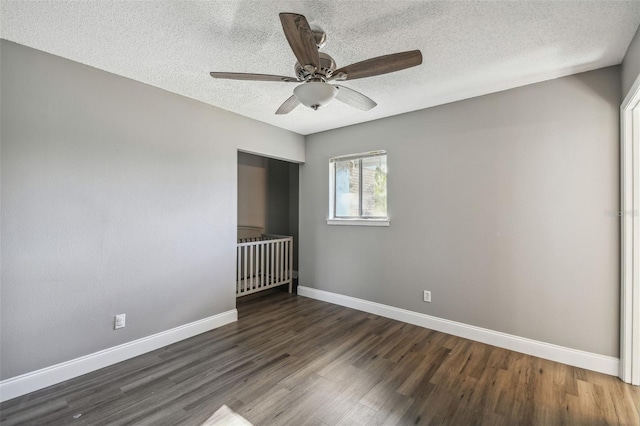 spare room with ceiling fan, dark wood-type flooring, and a textured ceiling