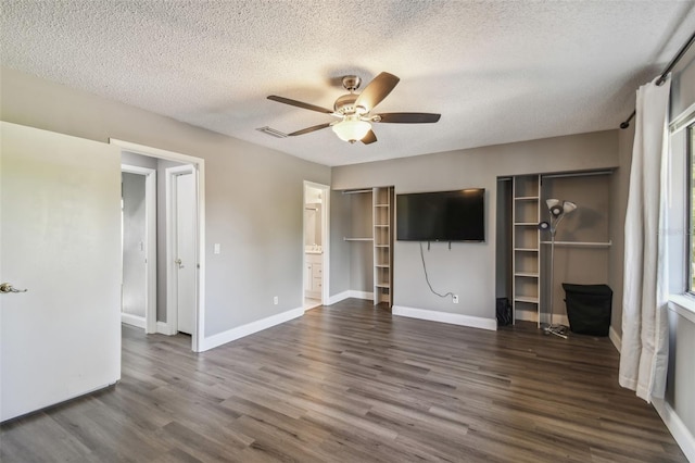 unfurnished bedroom with ceiling fan, connected bathroom, dark wood-type flooring, and a textured ceiling