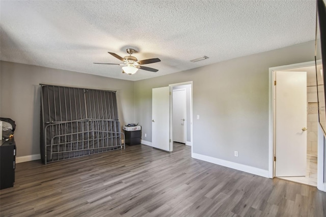 unfurnished bedroom featuring ceiling fan, a textured ceiling, connected bathroom, and hardwood / wood-style floors