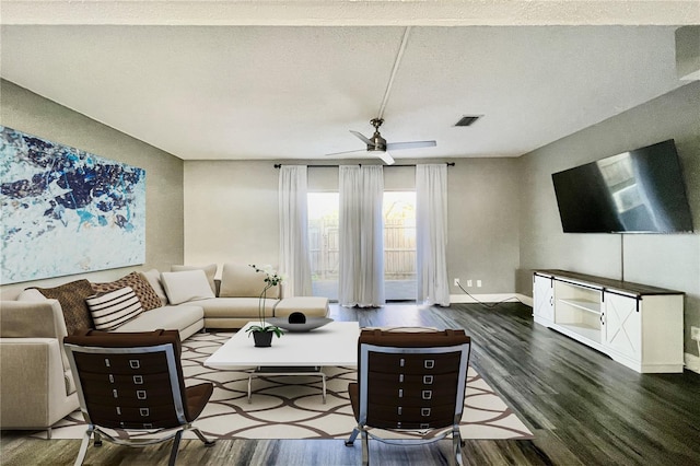 living room featuring ceiling fan, a textured ceiling, and dark hardwood / wood-style floors