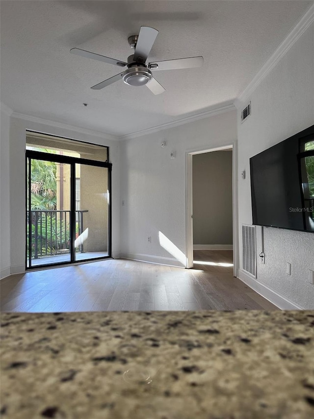 empty room with hardwood / wood-style flooring, ceiling fan, and crown molding