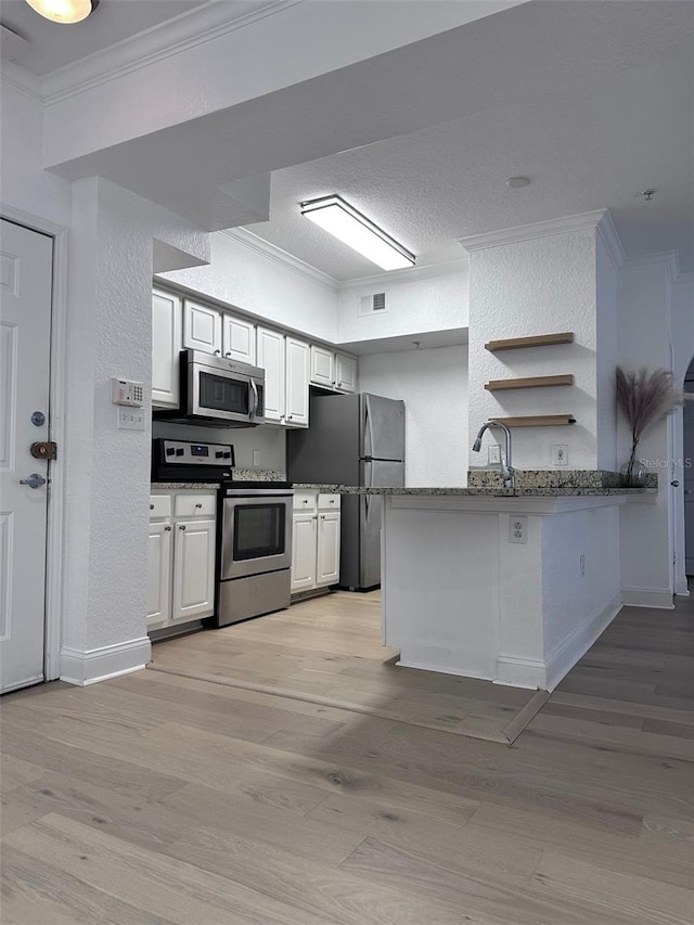 kitchen with kitchen peninsula, white cabinets, and stainless steel appliances