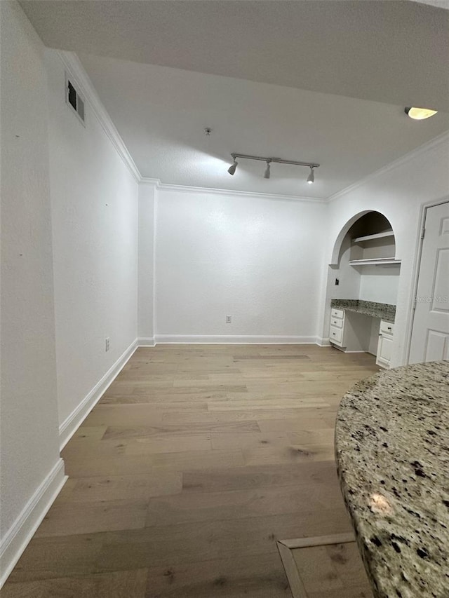 interior space featuring light wood-type flooring, built in desk, rail lighting, and crown molding