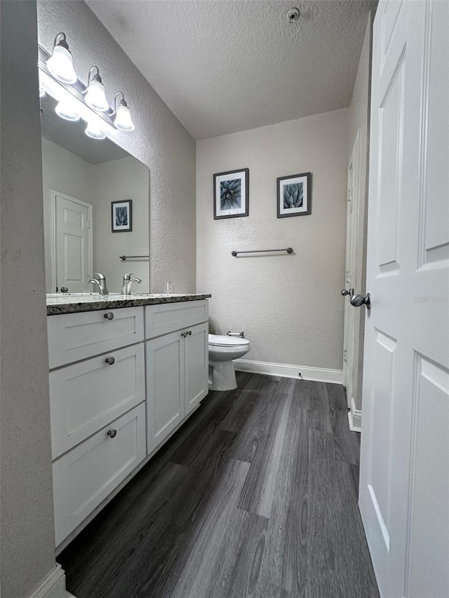 bathroom featuring toilet, vanity, a textured ceiling, and hardwood / wood-style flooring