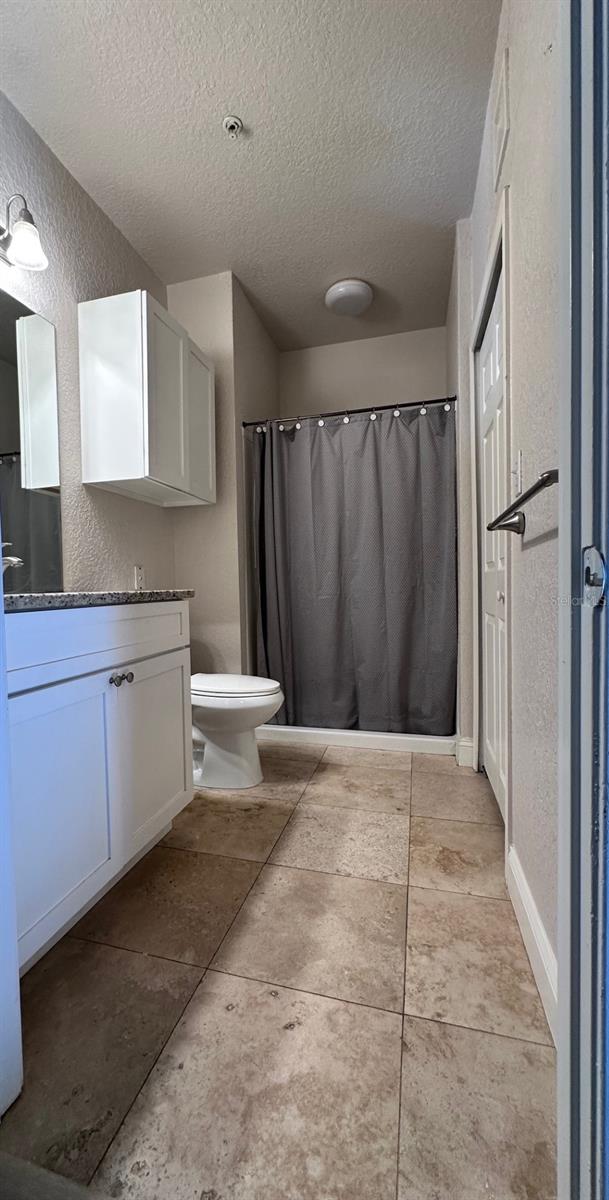 bathroom with tile patterned floors, vanity, toilet, and a textured ceiling