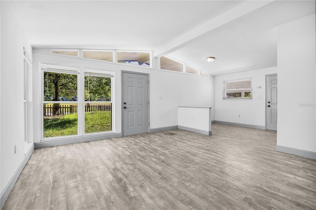 unfurnished living room featuring lofted ceiling with beams and light hardwood / wood-style floors