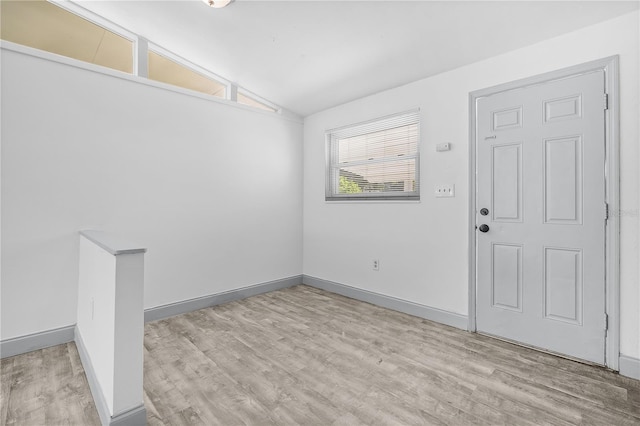 unfurnished room with light wood-type flooring and lofted ceiling