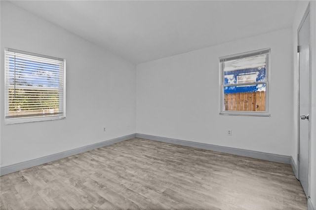 unfurnished room featuring light hardwood / wood-style floors and vaulted ceiling