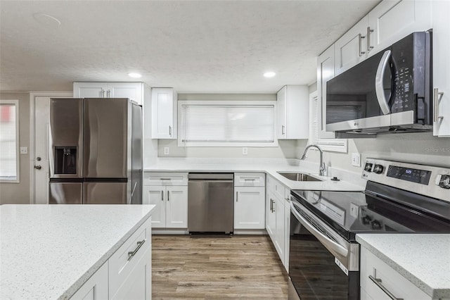 kitchen featuring white cabinetry, sink, stainless steel appliances, and light wood-type flooring