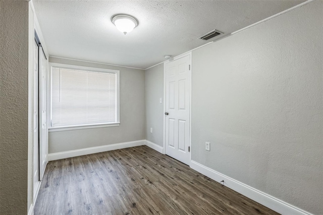 spare room with dark hardwood / wood-style flooring and a textured ceiling