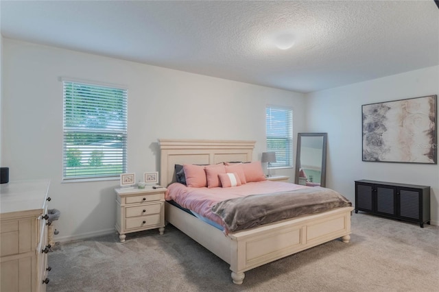 bedroom with multiple windows, light carpet, and a textured ceiling