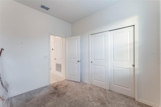 unfurnished bedroom featuring light colored carpet and a closet