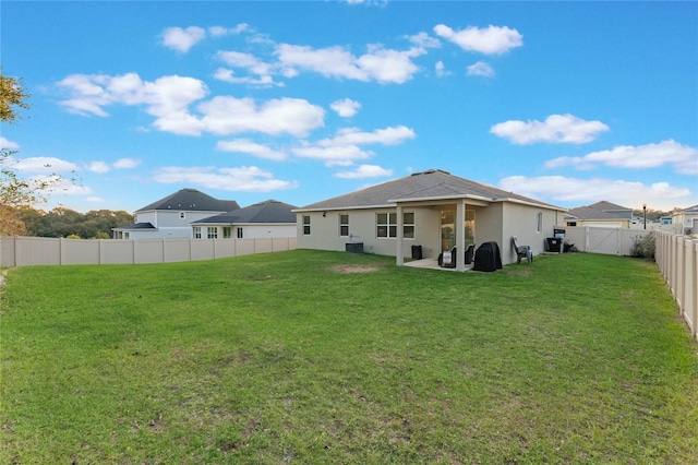 rear view of property with a lawn, a patio area, and central AC