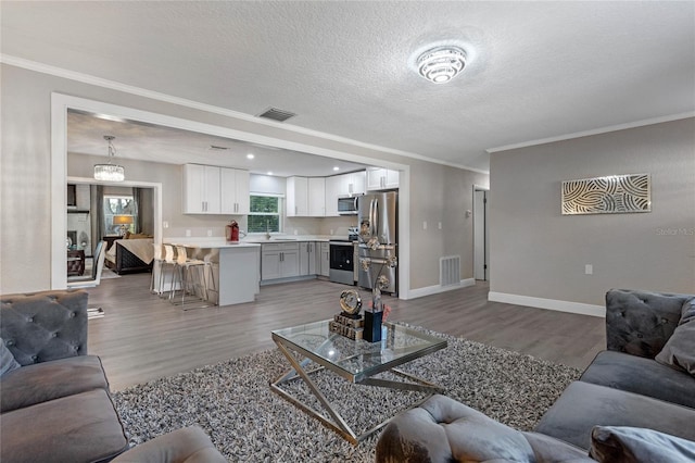 living room with ornamental molding, a textured ceiling, and light wood-type flooring