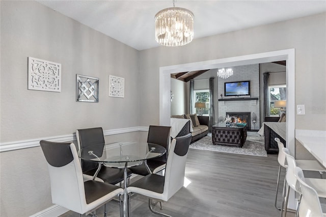 dining area with hardwood / wood-style floors, a fireplace, and a chandelier