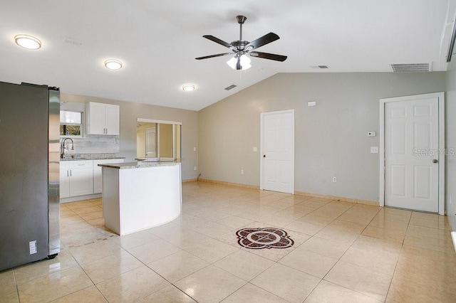 kitchen with ceiling fan, white cabinets, stainless steel fridge, vaulted ceiling, and light tile patterned floors