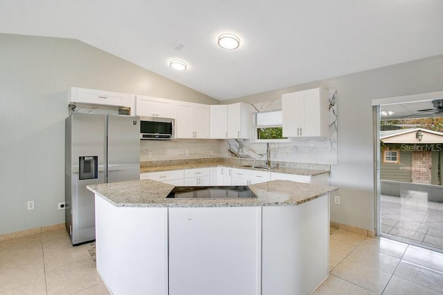 kitchen with light stone countertops, appliances with stainless steel finishes, white cabinets, a center island, and lofted ceiling