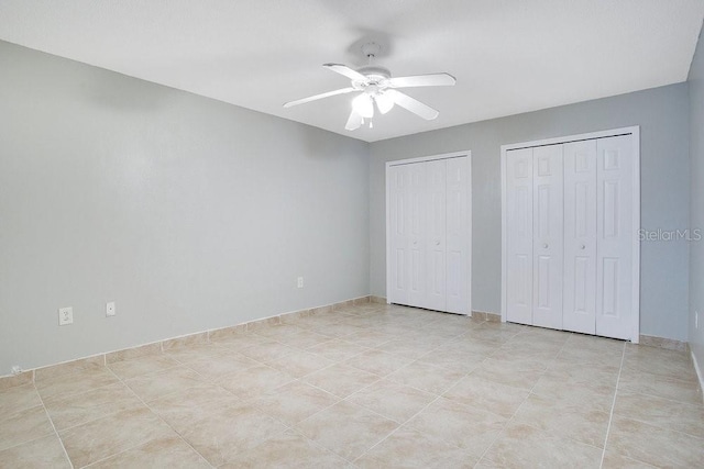 unfurnished bedroom featuring light tile patterned floors, ceiling fan, and multiple closets