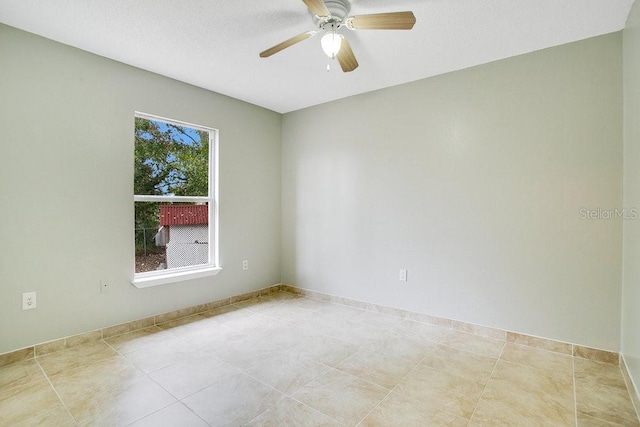 tiled spare room with ceiling fan