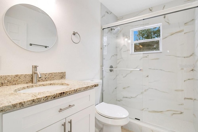 bathroom featuring a shower with door, vanity, and toilet