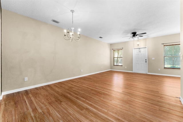 unfurnished room with a textured ceiling, light hardwood / wood-style flooring, and ceiling fan with notable chandelier