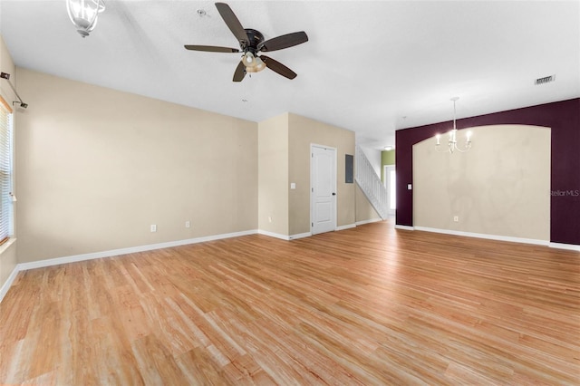 unfurnished living room with ceiling fan with notable chandelier and light hardwood / wood-style floors