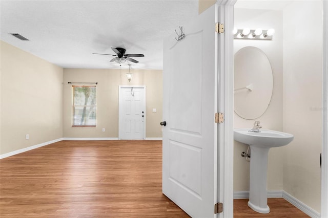 bathroom with hardwood / wood-style flooring, ceiling fan, sink, and a textured ceiling