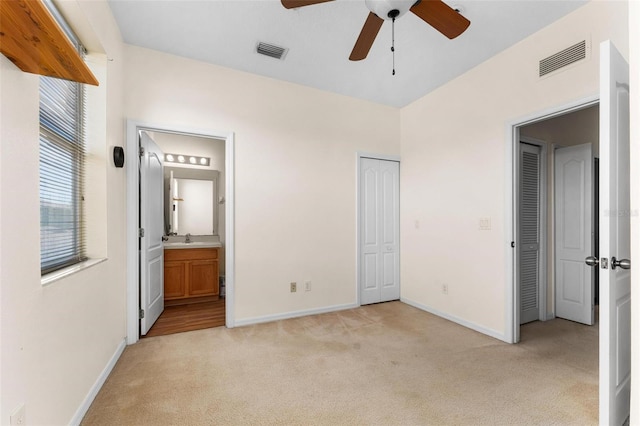 unfurnished bedroom featuring connected bathroom, ceiling fan, sink, and light carpet