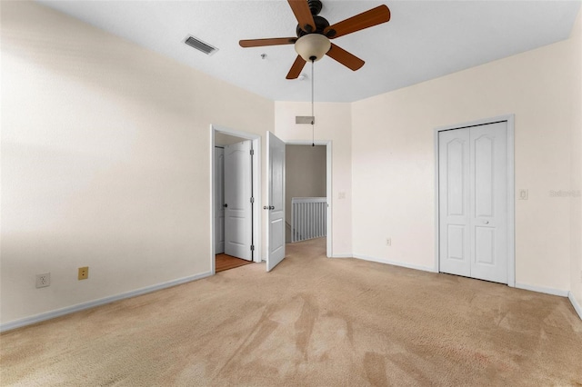 unfurnished bedroom with ceiling fan, light carpet, and a closet