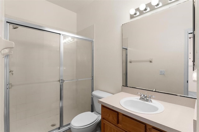 bathroom with a shower with door, vanity, and toilet