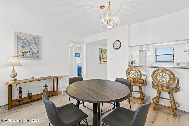 dining area featuring a chandelier, a textured ceiling, and light wood-type flooring