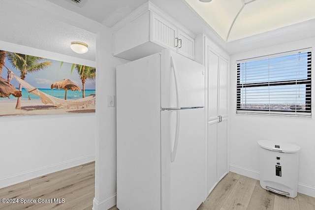 kitchen featuring light wood-type flooring, a textured ceiling, and white refrigerator