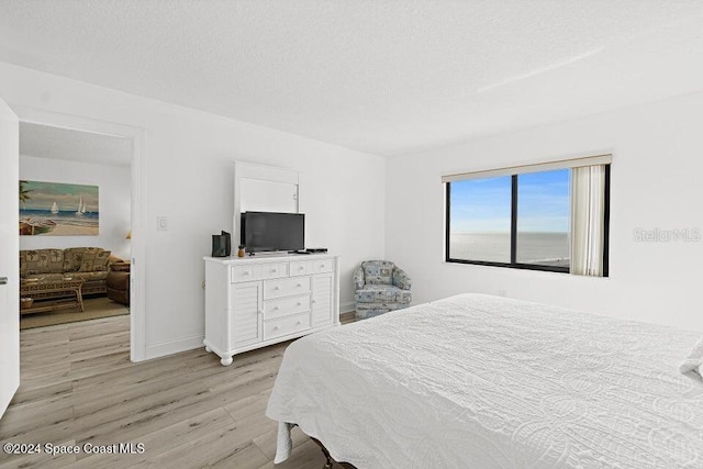 bedroom with a textured ceiling and light hardwood / wood-style flooring