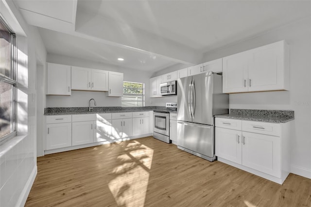 990 Sunrise Dr, Tarpon Springs, FL 34689 - kitchen with stainless steel appliances, light wood-style floors, white cabinets, light stone countertops, and a sink