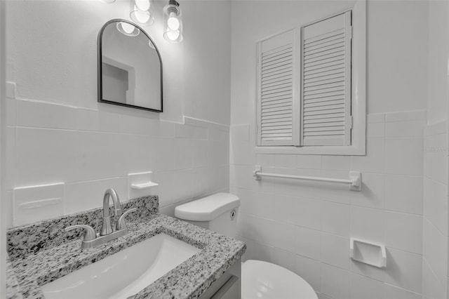 bathroom featuring vanity, toilet, and tile walls