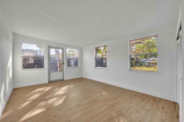 empty room with light hardwood / wood-style floors and lofted ceiling