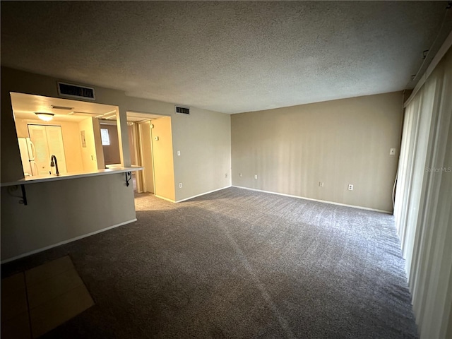 unfurnished living room with sink, carpet floors, and a textured ceiling