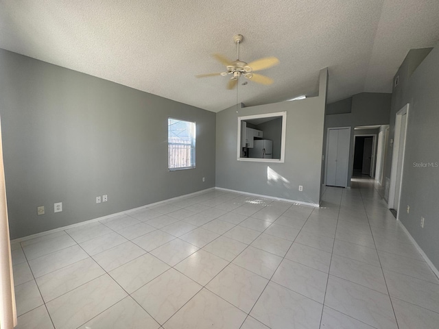 spare room with a textured ceiling, ceiling fan, light tile patterned floors, and lofted ceiling