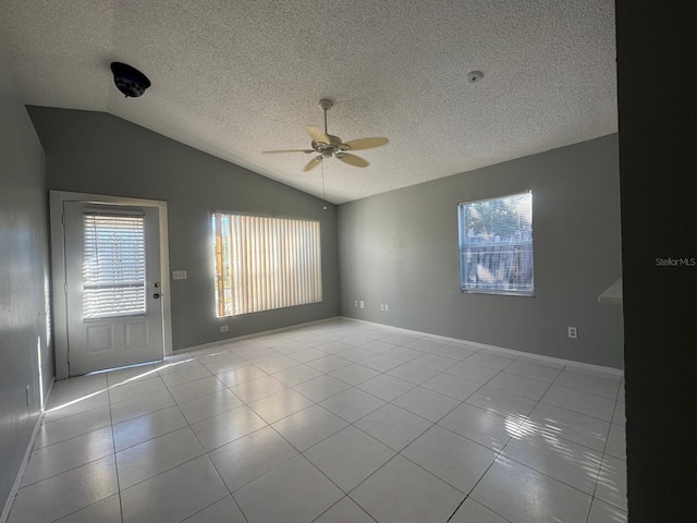 tiled empty room with a textured ceiling, ceiling fan, and vaulted ceiling