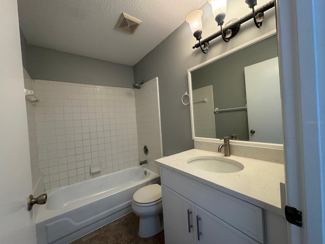 full bathroom with vanity, tile patterned floors, tiled shower / bath combo, toilet, and a textured ceiling