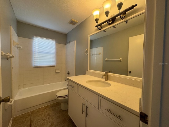 full bathroom featuring tile patterned flooring, a textured ceiling, toilet, vanity, and tiled shower / bath