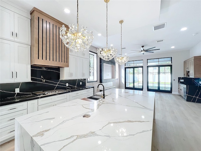 kitchen featuring decorative light fixtures, white cabinetry, and dark stone counters