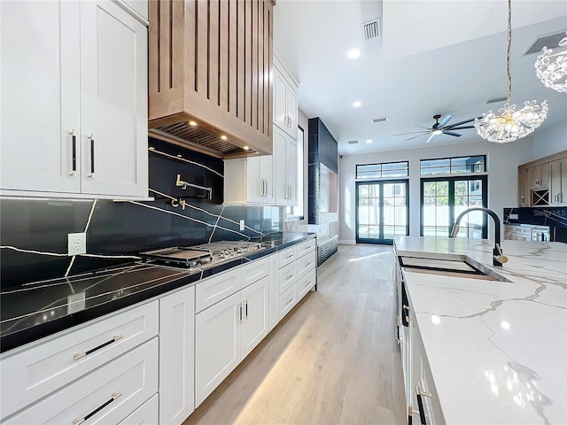 kitchen featuring tasteful backsplash, white cabinets, dark stone counters, and stainless steel gas cooktop