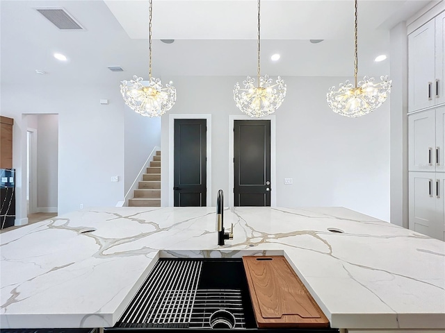 kitchen with white cabinets, an island with sink, and pendant lighting